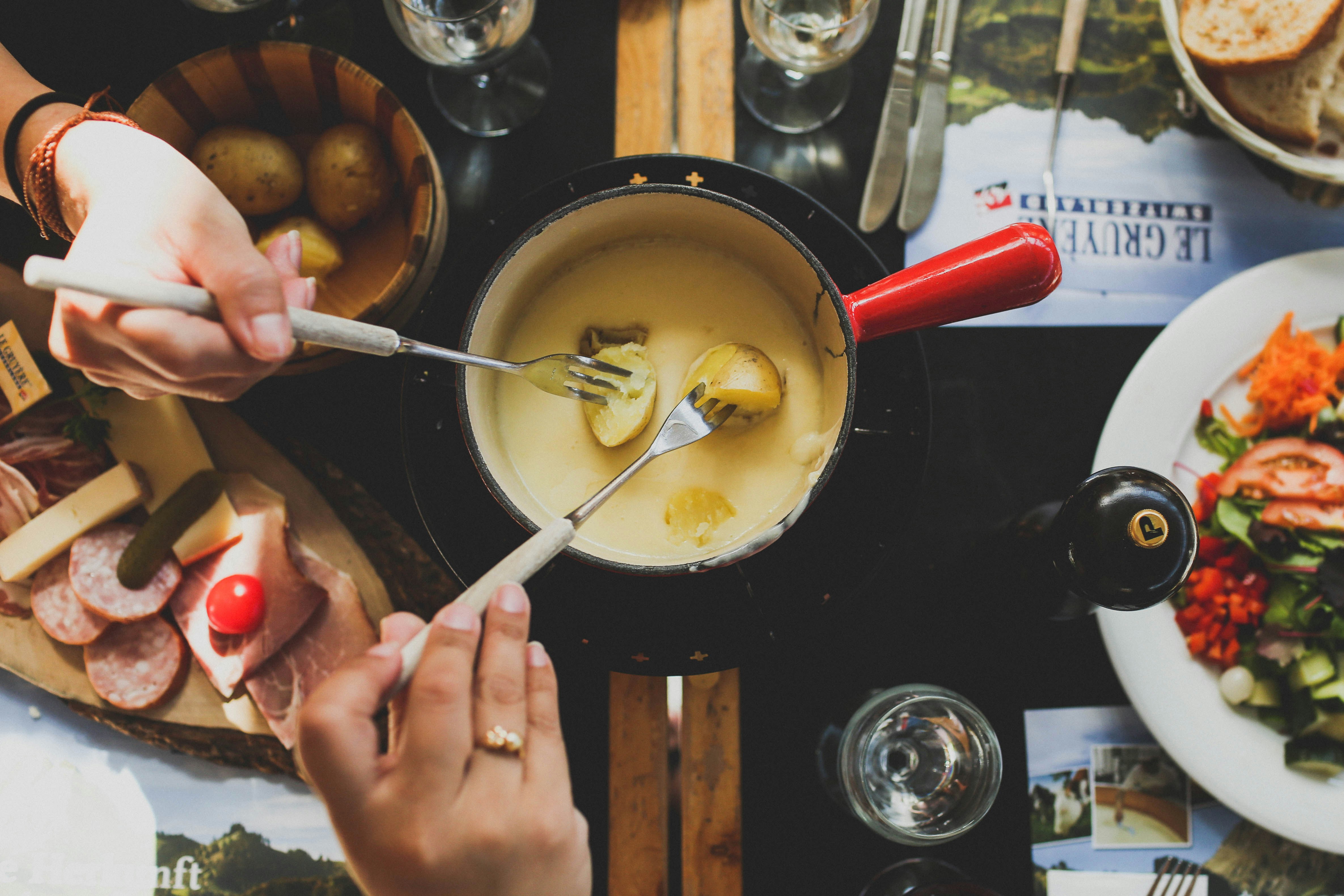 Traditional Alpine cheese fondue with potatoes, charcuterie and wine after skiing in Les Arcs, French Alps